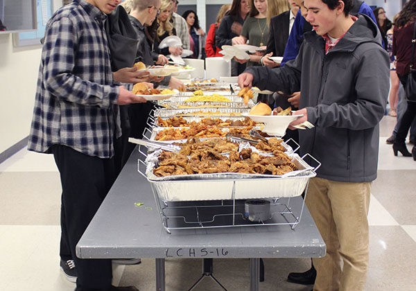 Athletes and their families fill their plates with food at the buffet. They sat together and ate before the awards ceremony.