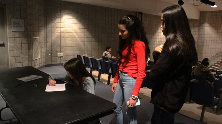 Allison Centanni (9), Veronica Gonzalez (9) and Charmagne Abangan (9) signing their names on the sign in sheet before the meeting starts. Every meeting they have to sign in to show you commitment to the club.