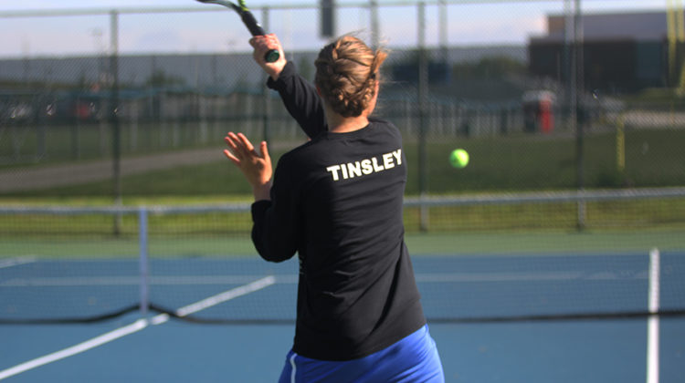 Kristina Tinsley (12) serves the ball during her last home match. Tinsley had never lost a home match during all of her four years.