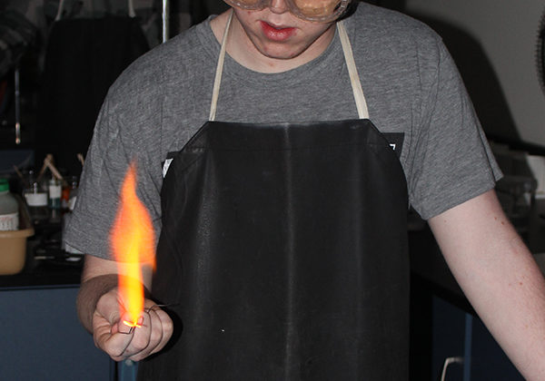 Bryce Hatfield (11) puts a wooden splint into a bunsen burner. Hatfield founded the Chemistry Club.