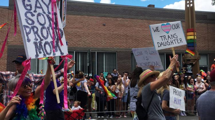 Proud parents of children from the LGBTQ+ community hold up signs showing their acceptance toward their children. The parents marched for four miles among an estimate of 6,000 other marchers.