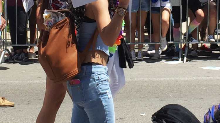 A person holding up a sign that says, “PRIDE” in rainbow letters and has a multi-colored fist. During the march, there were many people advocating for what they believed in.