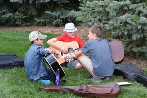 A few boys play guitar in a group. The Corn roast ended at 8 p.m. 