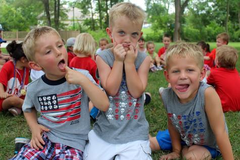 Three kids make silly faces to attempt to make the other children laugh on the last day of camp. The camp lasted seven weeks.  