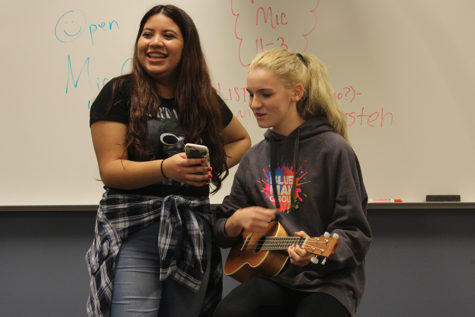 Jocelyn Hansen (9) holds up lyrics for Ava Solis (9) who sings “Spirits” by The Strumbellas. Hansen held up lyrics for multiple people throughout this Open Mic meeting. 