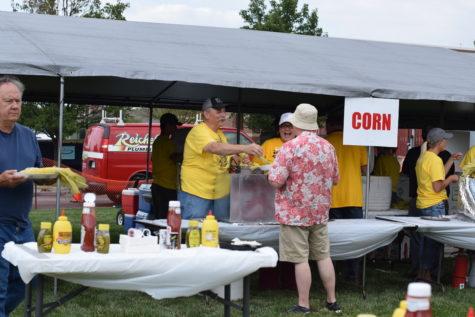 A man hands a husk of corn to an attendee. The Corn Roast took place on Aug. 11. 